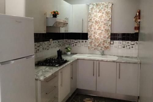 a kitchen with white cabinets and a sink and a window at Maisons Maktoub Djerba in Al Maqārisah