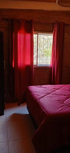 a bedroom with a bed and a window with red curtains at lo de la Gri in El Volcán