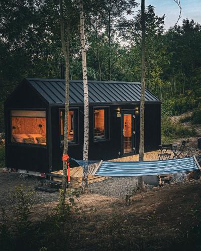 a black tiny house with a hammock in front of it at OtuliLas - Tiny House in Komarno