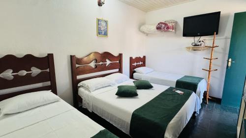 a room with two beds and a flat screen tv at Pousada Jara in Conservatória