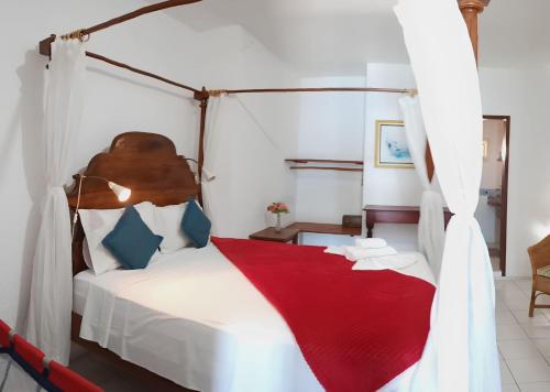 a bedroom with a canopy bed with a red blanket at Pousada Azul Marinho in Canoa Quebrada