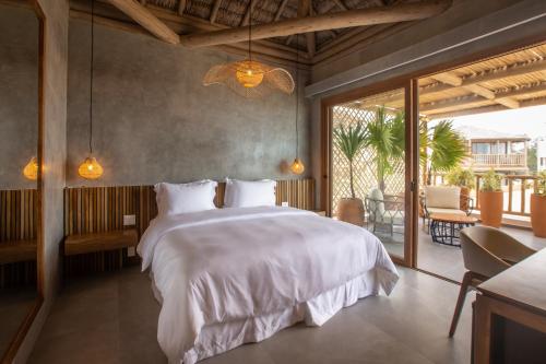 a bedroom with a large white bed and a balcony at Yemanjá Hotel by Preabeach Experience in Prea