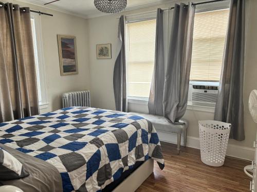 a bedroom with a blue and white checkered bed and windows at The Bushnell Suite C2 in Hartford