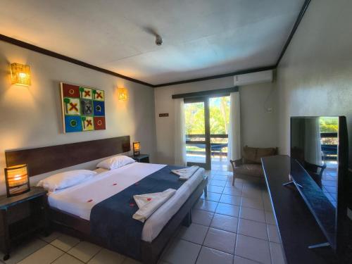 a bedroom with a large bed and a television at Porto Zarpa Hotel in Praia do Forte