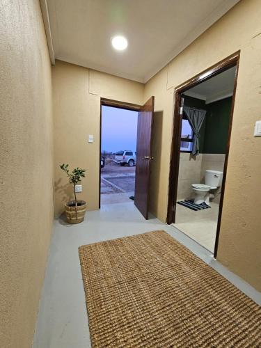 a hallway with a bathroom with a toilet and a rug at Pi-Buddy Lodge and Bushcamp in Outjo