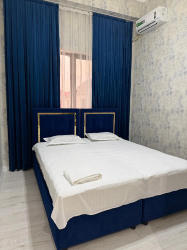 a bed in a room with blue curtains at Nogai Karavan in Türkistan