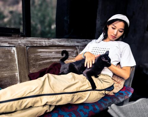 a woman sitting on a bench with a black cat at Wolf Totem Steam Punk Guesthouse in Pisac
