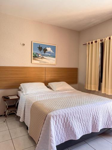 a bedroom with a bed and a picture of a beach at Pousada Missare in Canoa Quebrada