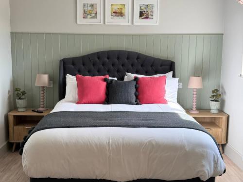 a bedroom with a large bed with pink pillows at Foxglove in Bicester