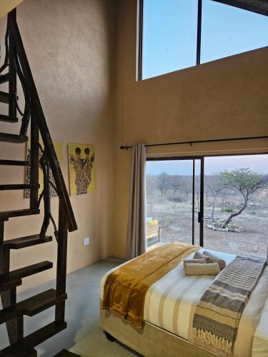 a bedroom with a bed and a large window at Pi-Buddy Lodge and Bushcamp in Outjo