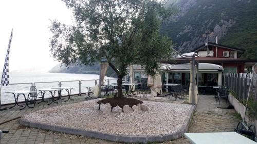 a tree in the middle of a courtyard with tables and chairs at Villa Monica in Malcesine