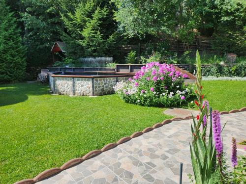 a garden with purple and white flowers in a yard at Casa Turta Dulce in Buşteni