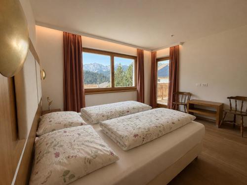a bedroom with two beds and a large window at Ciasa de Zeno in La Valle