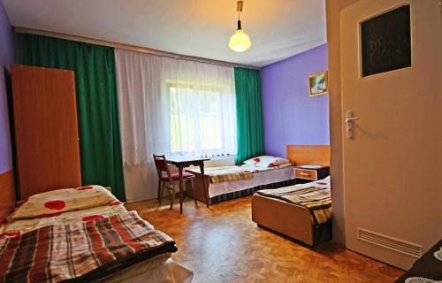 a room with two beds and a table with a chair at Juhas in Zwardoń