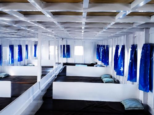 a room with blue and white beds and blue curtains at Azmy Adventure in Pawenang