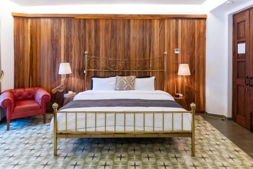 ein Schlafzimmer mit einem Bett und einem roten Stuhl in der Unterkunft Del Carmen Concept Hotel Boutique by Chai in Guadalajara