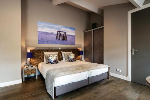 a bedroom with a bed and a painting on the wall at Hof van Alexander Boutiquehotel in Renesse