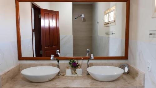 two white sinks in a bathroom with a mirror at Pousada Azul Marinho in Canoa Quebrada