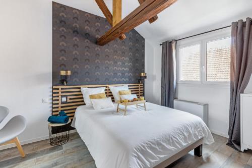 a bedroom with a large white bed with a wooden headboard at Le Bartholdi in Andolsheim