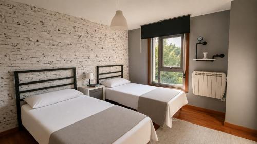 a bedroom with two beds and a brick wall at O IGREXARIO Vacacional in Cangas de Morrazo
