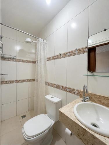 a white bathroom with a toilet and a sink at Casa Luna in Marau
