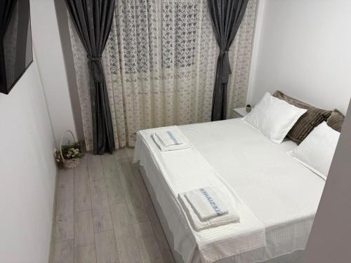 a bedroom with a white bed and a curtain at Transfăgărașean Gateway in Curtea de Argeş