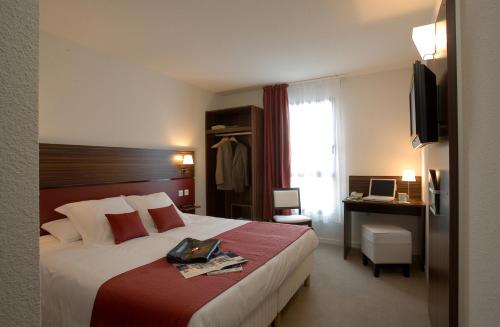 a hotel room with a bed and a desk at Hôtel Le Palladior Voiron in Voiron