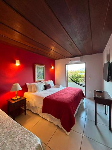 a bedroom with a large bed with a red wall at Pousada Solar D Alcina in Paraty