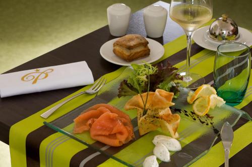 a table with a plate of food and a glass of wine at Hôtel Le Palladior Voiron in Voiron