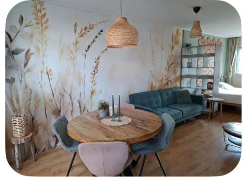 a living room with a table and a blue couch at Sfeervolle Studio 't kapucijntje Ossendrecht, near Antwerp in Ossendrecht