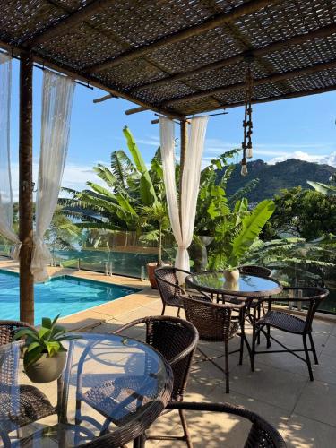a patio with tables and chairs and a pool at Pousada Costa dos Corais in Mangaratiba
