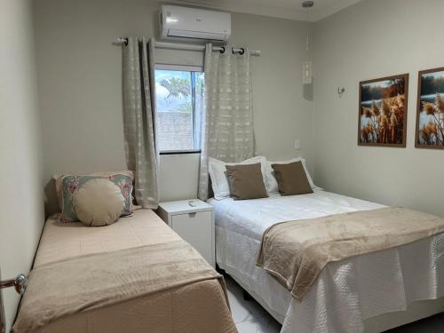a bedroom with two beds and a window at Chalés Sítio Frade in Martins