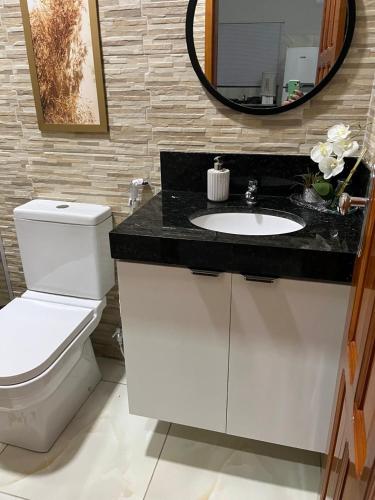 a bathroom with a toilet and a sink and a mirror at Chalés Sítio Frade in Martins