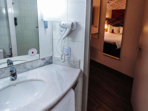 a bathroom with a sink and a phone on the wall at Ibis Maringa in Maringá