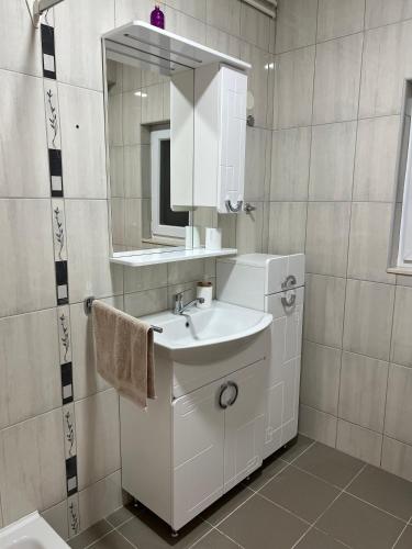 a white bathroom with a sink and a mirror at Garden View Apartment in Čapljina