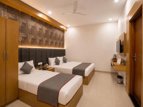 a hotel room with two beds and a tv at Hotel Rose Inn in Prayagraj