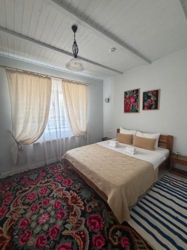 a bedroom with a large bed and a rug at Pensiunea Casa Veche in Palanca