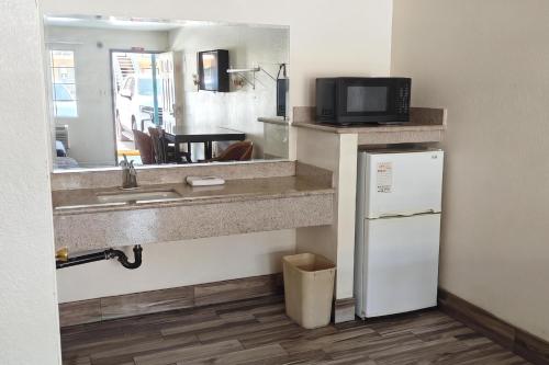 a kitchen with a counter with a sink and a refrigerator at Del Playa Inn Oxnard Near Camarillo in Oxnard