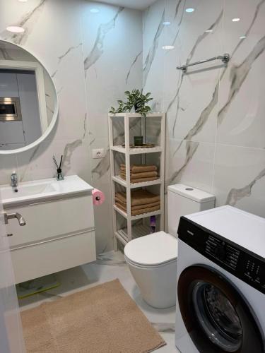 a bathroom with a toilet sink and a washing machine at Cura Marina 2 in Playa del Cura