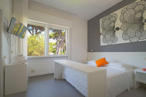 a bedroom with a white bed and a window at Hotel La Bussola in Marina di Massa