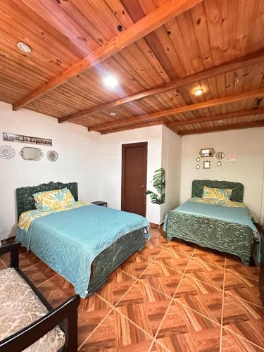 two beds in a room with wooden ceilings and wooden floors at Padua Finca Hotel in Chachagüí