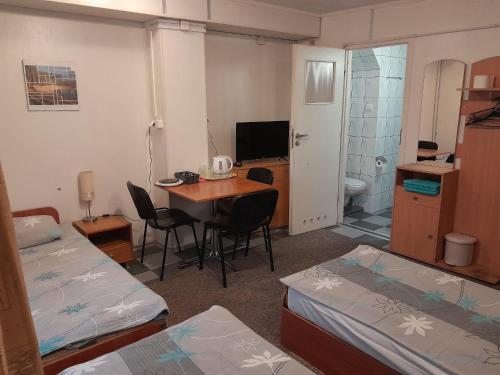 a room with two beds and a table and a bathroom at Pokoje Slomkowscy in Łódź