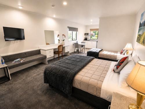 a hotel room with a large bed and a desk at Settlers Motor Lodge in Lower Hutt