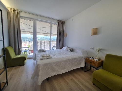 a bedroom with a bed and a chair and a window at Albergue EL CASTILLO in Sarria