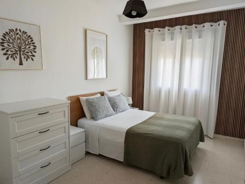 a bedroom with a white bed and a dresser at Apartamento Casa Balina II in Dúrcal