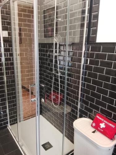 a bathroom with a shower with a red box on the toilet at KALEIDO Hostel in Genoa