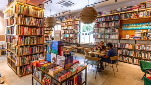 two people sitting at a table in a library at Hotel Libreria Cafe de Pombal in Santa Marta