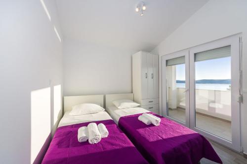 two beds in a bedroom with purple sheets and towels at Apartment Paulo&Lorenco in Sveti Filip i Jakov