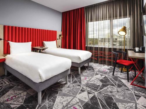 a hotel room with two beds and a red curtain at ibis Styles London Ealing in London