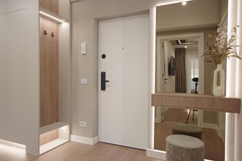 a hallway with a door and a stool and a mirror at Bacovia Grand Apartment- Free Parking in Bacău